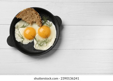 Delicious fried eggs served with bread on white wooden table, top view. Space for text