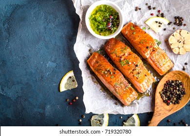 Delicious Fried Salmon Fillet, Seasonings On Blue Rustic Concrete Background. Cooked Salmon Steak With Pepper, Herbs, Lemon, Garlic, Olive Oil, Spoon. Space For Text. Fish For Dinner. Healthy Eating