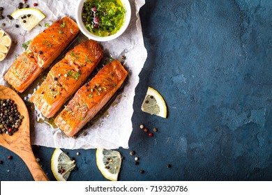 Delicious fried salmon fillet, seasonings on blue rustic concrete background. Cooked salmon steak with pepper, herbs, lemon, garlic, olive oil, spoon. Space for text. Fish for dinner. Healthy eating