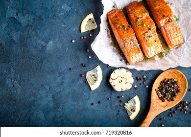 Delicious Fried Salmon Fillet With Seasonings On Blue Rustic Concrete Background. Cooked Salmon Steak With Pepper, Herbs, Lemon, Garlic, Cooking Spoon. Space For Text. Fish For Dinner. Healthy Eating