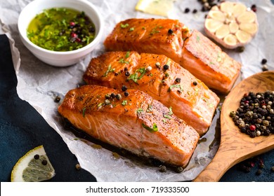 Delicious fried salmon fillet, seasonings on blue rustic concrete table. Cooked salmon steak with pepper, herbs, lemon, garlic, olive oil, spoon. Grilled fresh fish. Fish for healthy dinner. Close-up