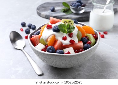 Delicious Fruit Salad With Yogurt On Grey Table