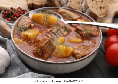 Delicious goulash in bowl on dark wooden table, closeup - Shutterstock ID 2368692497