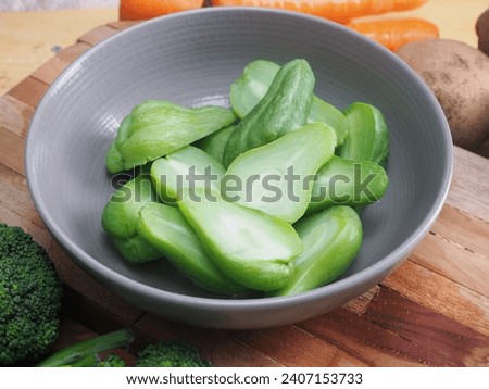 delicious green chayote in a ceramic bowl, full of nutrition such as vitamin and viber. Broccoli, carrot and potatoes as a background