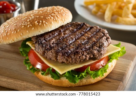 A delicious grilled Angus burger with cheese, lettuce, and tomato on a sesame seed bun.
