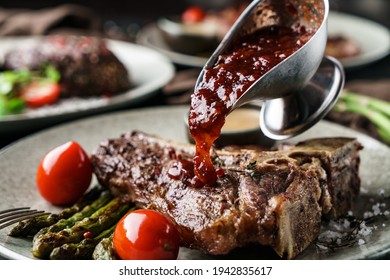 Delicious Grilled Beef Steak With Spices On Plate With Tomatoes And Berry Sauce Over Dark Background. Concept Of Bbq Food, Close Up