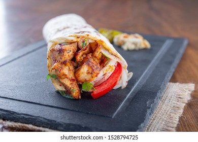 Delicious Grilled Chicken Kebab Wrap With Onion Tomato And Parsley On Black Stone Plate.