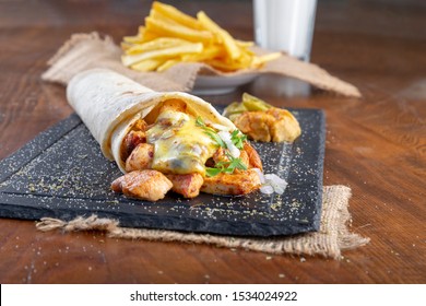 Delicious Grilled Chicken Kebab Wrap Melting Cheddar Cheese On Top With Turkish Drink Ayran And Golden Fried French Fries On Black Stone Plate.