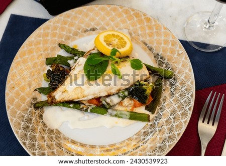 Delicious grilled fillet of gilthead bream (dorada) with lemon, baked vegetables and white sauce