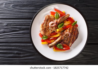 Delicious Grilled Pork Chop With Bell Peppers, Onions And Basil Close-up In A Plate On The Table. Horizontal Top View From Above
