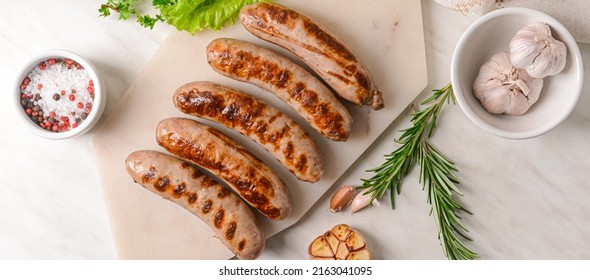 Delicious grilled sausages and spices on light background, top view