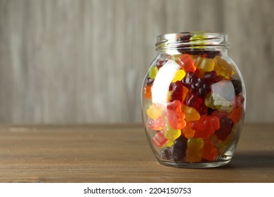 Delicious Gummy Bear Candies In Jar On Wooden Table. Space For Text
