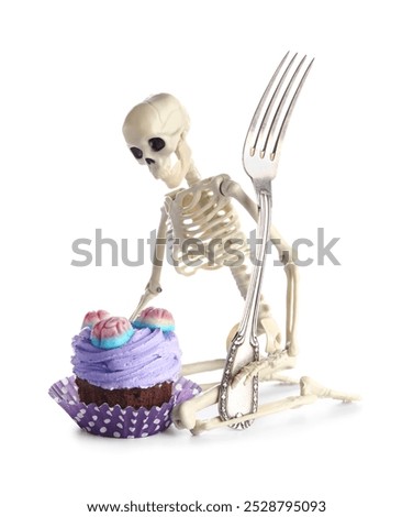 Delicious Halloween cupcake with candies and skeleton on white background