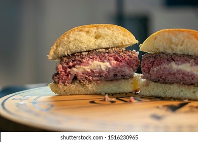 Delicious Halved Jucy Lucy Burger Stuffed With Cheese On A Wooden Board