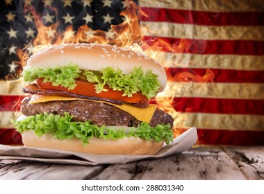 Delicious hamburger with fire flames and american flag on wooden background - Powered by Shutterstock