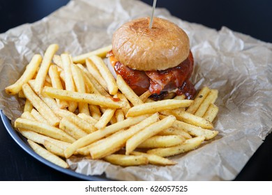 Delicious Hamburger With Tomato Ketchup Sauce Served On Plate With Golden French Fries In Fast Food Cafe Menu.Restaurant Dinner Food Close Up.Roasted Hand Crafted Burger