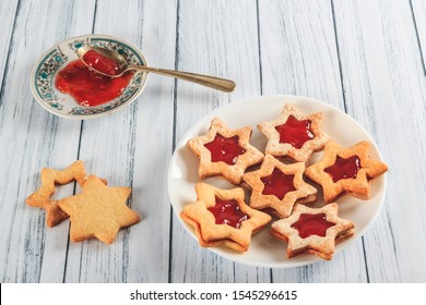 Delicious handmade star cookies with jam on a plate on a rustic white wooden table. Strawberry, raspberry, currant jam cookies. Another dish has jam to fill more cookies. Creative pastry. - Powered by Shutterstock