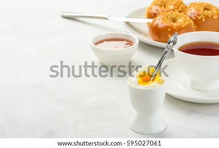 Delicious and healthy breakfast of boiled egg and brioche buns with black tea on a light background. Copy space,soft focus.