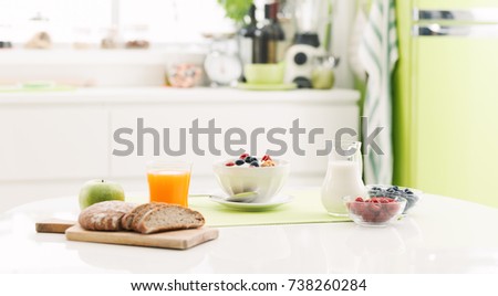 Delicious healthy breakfast at home with cereals, milk and fresh fruit; kitchen interior on the background