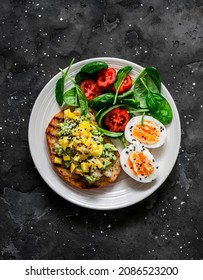 Delicious Healthy Breakfast, Snack - Sandwich With Avocado, Shrimp, Mango Salsa, Boiled Egg And Spinach Tomatoes Salad On A Dark Background, Top View