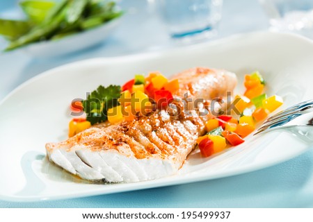 Delicious healthy grilled fish fillet served on a platter with a colorful fresh salad for a tasty seafood dinner