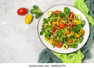Delicious and healthy salad with beans mung, avocado, leek, cherry tomatoes, corn lettuce on light gray background. Dressed with vinaigrette sauce. Concept of dietary and healthy food