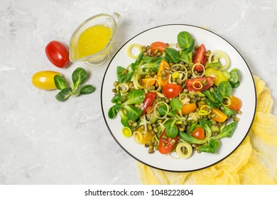 Delicious and healthy salad with beans mung, avocado, leek, cherry tomatoes, corn lettuce on light gray background. Dressed with vinaigrette sauce. Concept of dietary and healthy food