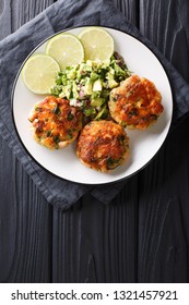 Delicious Healthy Salmon Fritters With Avocado Salsa And Lime Closeup On A Plate On The Table. Vertical Top View From Above
