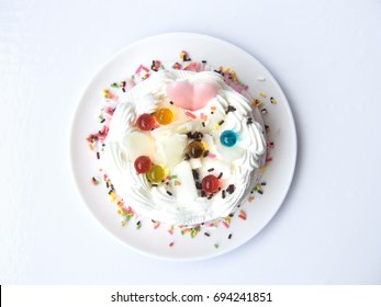 Delicious Heart Of Love Sweet Cake. The Vanilla Cream Cake Decorated With Pink And White Chocolate, Jelly Balls And Color Sugar On A White Plate. Close Up Top View, Isolated On White Background.