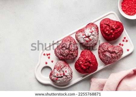 Delicious heart shaped red velvet cupcakes decorated with sprinkles on a ceramic board. Valentines day celebration. top view, copy space