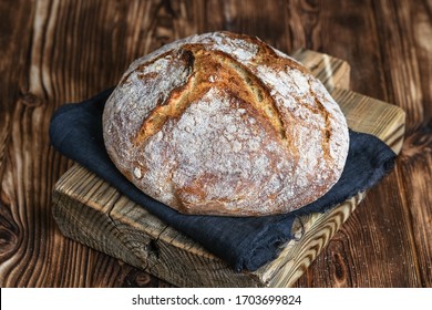 Delicious homemade bread on a dark napkin a cutting board on a rustic background. - Shutterstock ID 1703699824