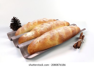 delicious homemade butter bread is in rose gold color baguette bread tray on the white table with pinecone and cinnamon sticks on white background in the bakery shop during Chritmas winter season
