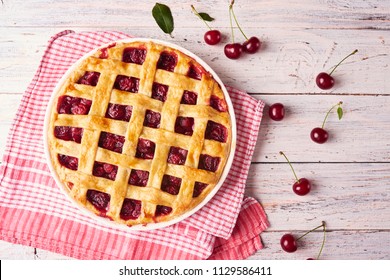 Delicious Homemade Cherry Pie with a Flaky Crust on rustic wooden white background. Top view