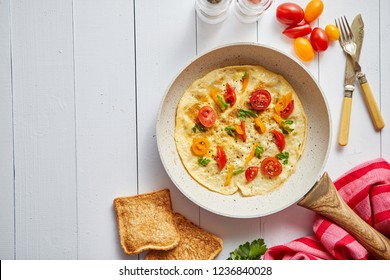 Delicious homemade egg omelette with tomatoes and parsley. Sprinkled with fresh pepper. Served with toasts. Top view with copy space. - Powered by Shutterstock