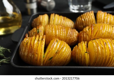 Delicious homemade Hasselback potatoes in baking pan on black table, closeup