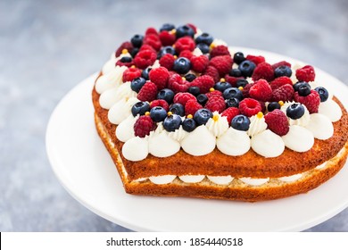 Délicieux gâteau à la vanille en forme de coeur fait maison décoré de crème et de baies fraîches