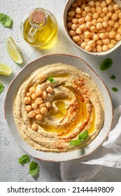 Delicious and homemade hummus with lime and mint leaves. Hummus served served olive oil and mint leaves.