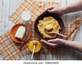 Delicious Homemade Pumpkin Porridge On Wooden Background. Elderly Woman's Hands Over Food. Healthy Vegan Food With Autumn Pumpkin Porridge.