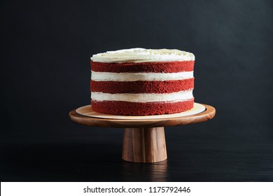 Delicious Homemade Red Velvet Cake On Wooden Stand Against Black Background