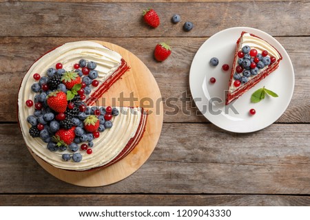 Delicious homemade red velvet cake with fresh berries on wooden table, top view