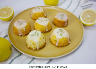 Delicious Homemade Small Fresh  Lemon Drizzle Cake Creaming Method Type With Thyme On Yellow Circle Plate With Fresh Lemon Slice, On A Tablecloth With Copy Space For Text And Blur Background. Coffee