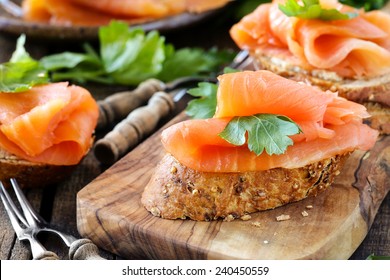 Delicious homemade smoked salmon gluten free canape garnished with a fresh parsley leaf on rustic wood