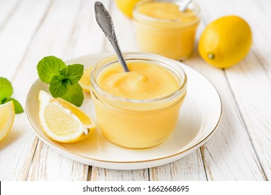 Delicious homemade tangy lemon curd decorated with fresh fruit in a glass jars on rustic wooden background