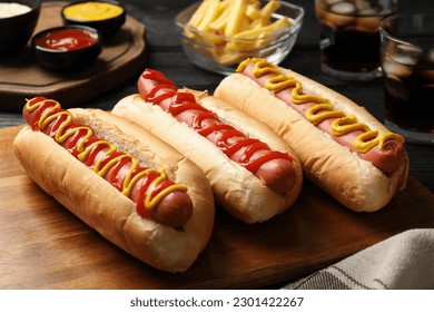 Delicious hot dogs with mustard and ketchup on black wooden table, closeup - Powered by Shutterstock