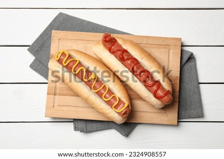 Delicious hot dogs with mustard and ketchup on white wooden table, top view