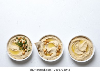 Delicious hummus with olive oil, chickpeas and pita in bowls on light textured table, flat lay. Space for text