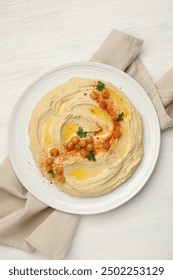 Delicious hummus with olive oil, chickpeas and paprika on white wooden table, top view