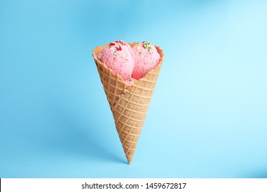 Delicious ice cream in wafer cone on blue background