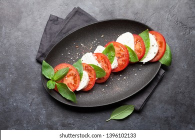 Delicious Italian Caprese Salad With Ripe Tomatoes, Fresh Garden Basil And Mozzarella Cheese. Top View Flat Lay