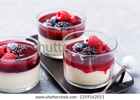 Delicious italian dessert panna cotta with berry sauce, fresh berries and mint on gray background. - Image